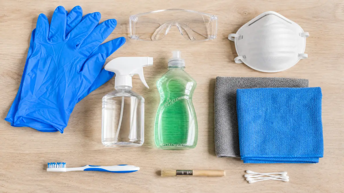 Supplies to remove mold from windows: gloves, mask, goggles, spray bottle, cloths and brushes